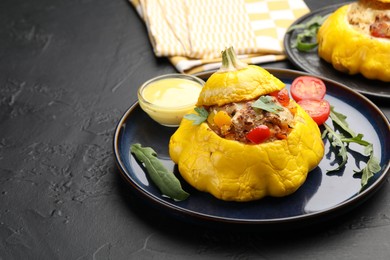 Photo of Tasty stuffed pattypan squash with sauce on black table, closeup. Space for text