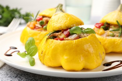 Photo of Tasty stuffed pattypan squashes on grey table, closeup