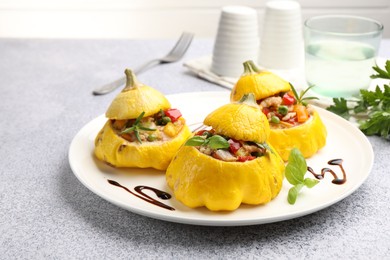 Photo of Tasty stuffed pattypan squashes on grey table, closeup