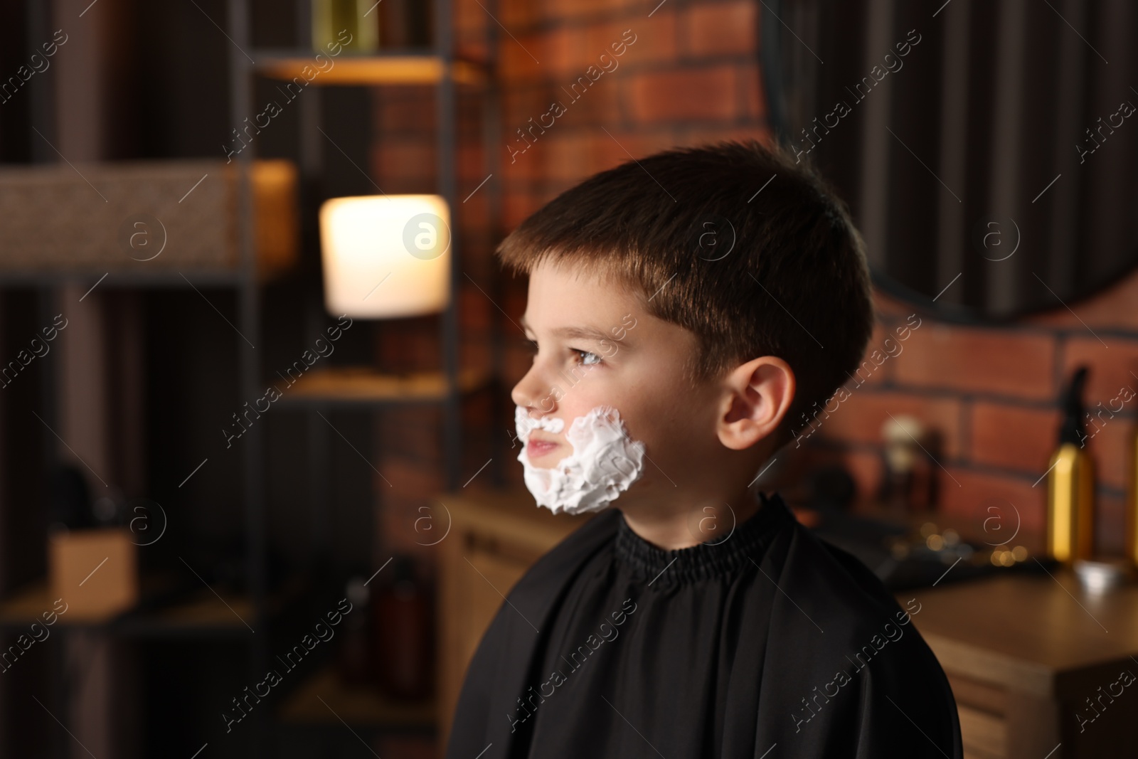 Little boy with shaving foam on his face in barbershop, space for text Photo of Little boy with shaving foam on his face in barbershop, space for text