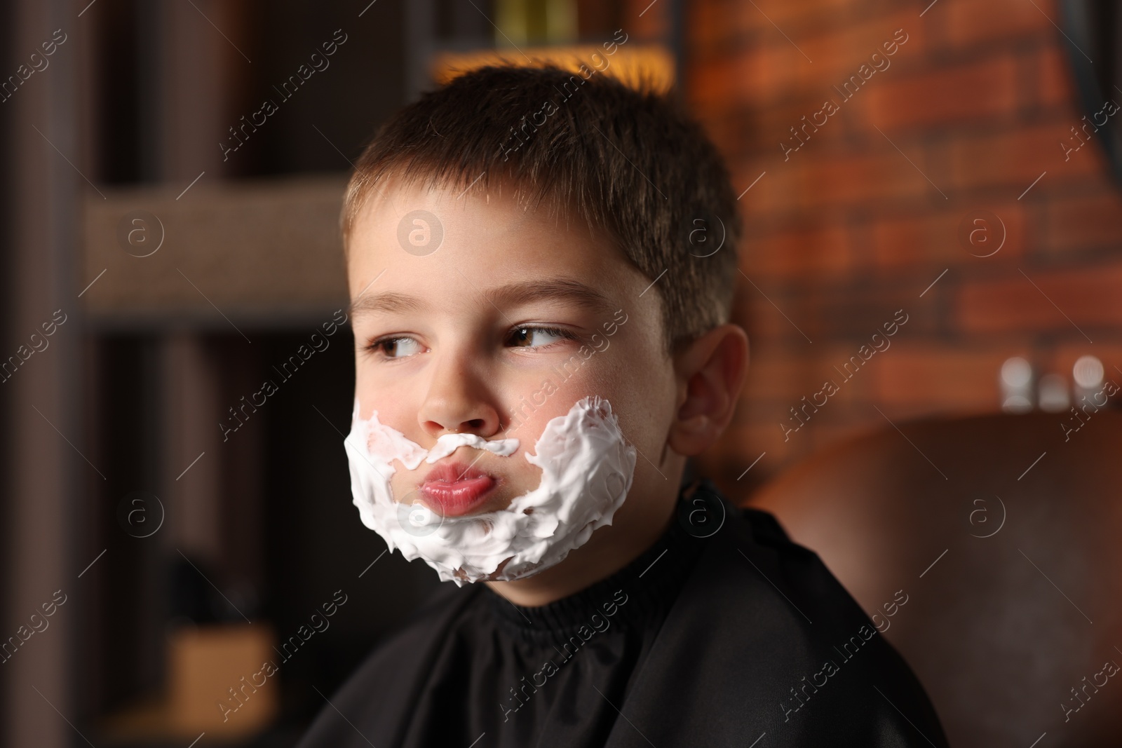 Little boy with shaving foam on his face in barbershop Photo of Little boy with shaving foam on his face in barbershop