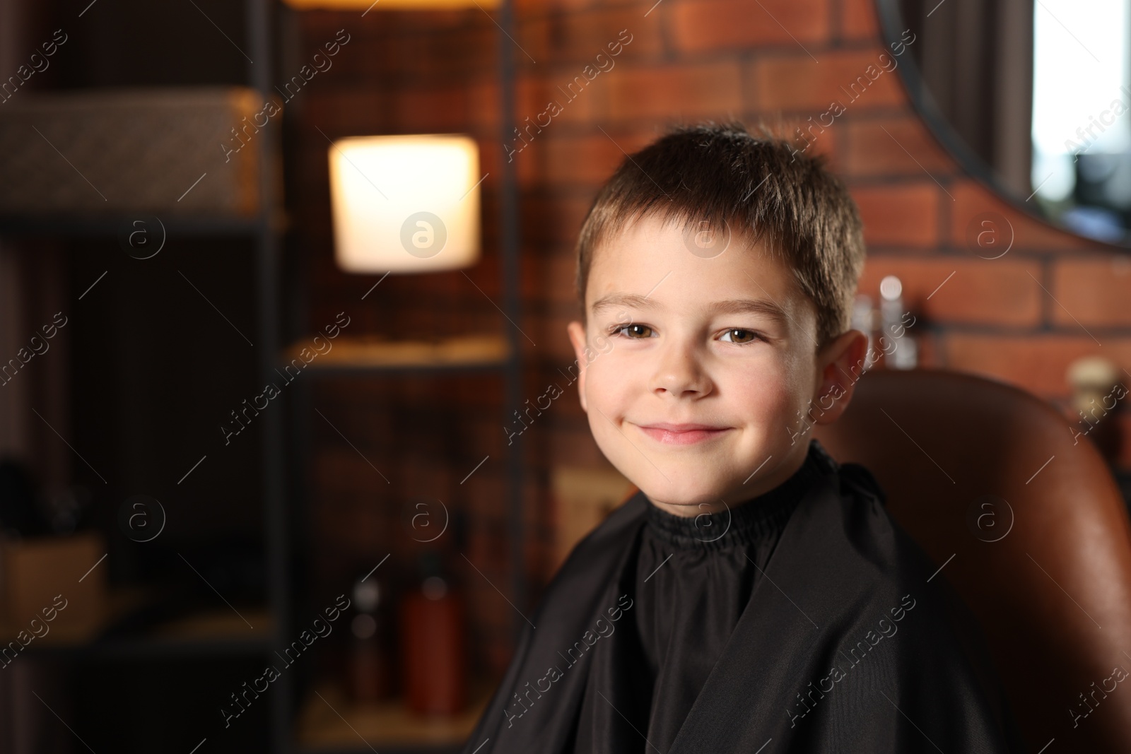 Photo of Portrait of cute little boy in barbershop, space for text
