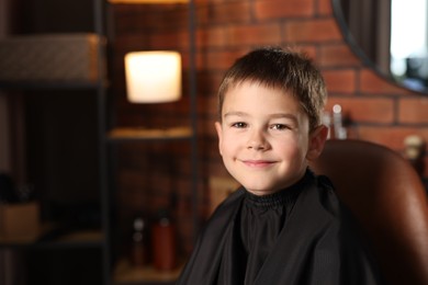 Photo of Portrait of cute little boy in barbershop, space for text