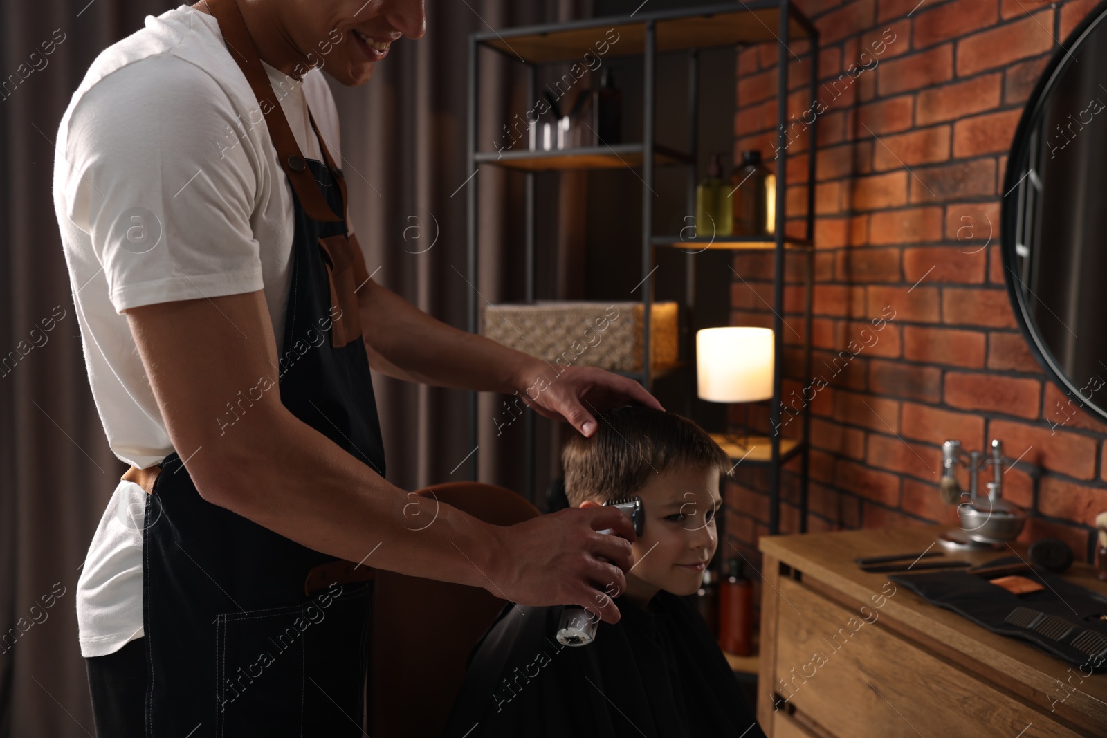 Professional barber working with little boy in barbershop, closeup Photo of Professional barber working with little boy in barbershop, closeup