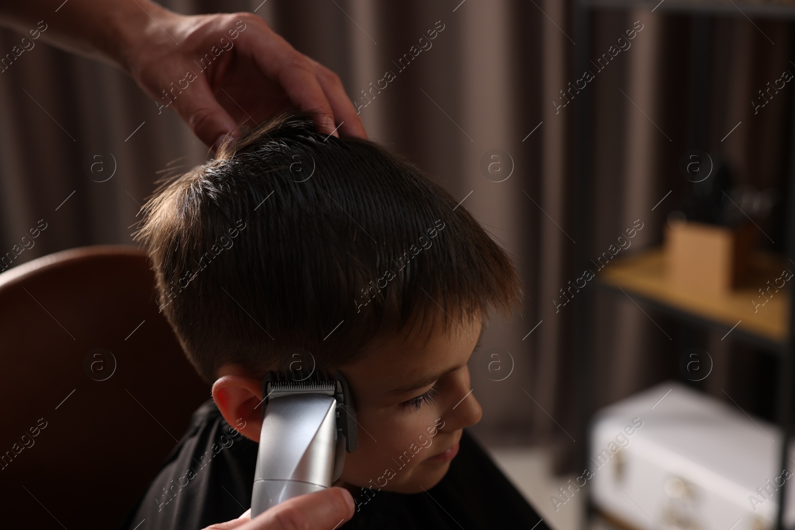 Professional barber working with little boy in barbershop, closeup Photo of Professional barber working with little boy in barbershop, closeup