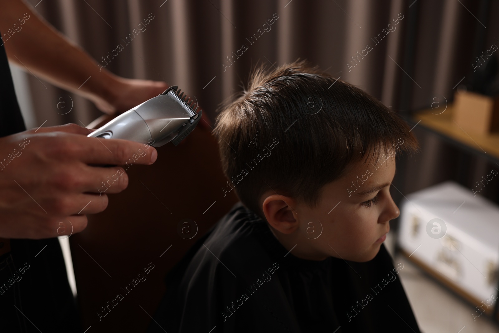 Professional barber working with little boy in barbershop, closeup Photo of Professional barber working with little boy in barbershop, closeup