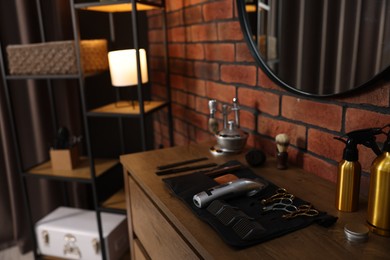 Photo of Different barber's tools on wooden cabinet in barbershop, closeup