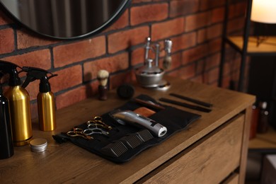 Photo of Different barber's tools on wooden cabinet in barbershop, closeup