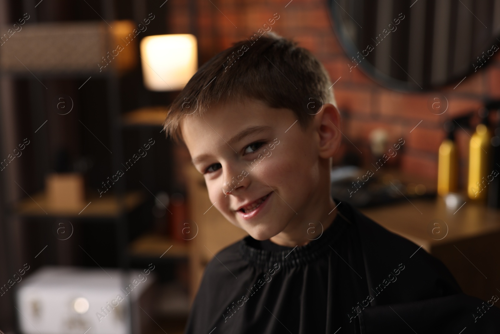 Photo of Portrait of cute little boy in barbershop, space for text