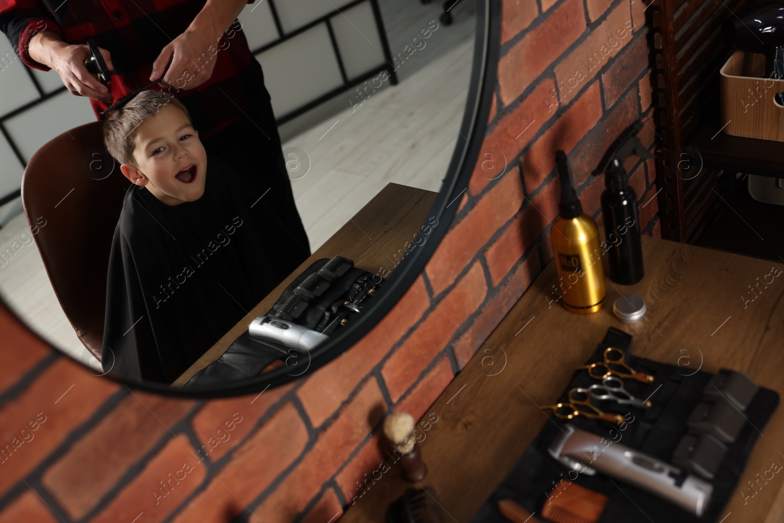 Professional barber working with little boy in barbershop, closeup Photo of Professional barber working with little boy in barbershop, closeup