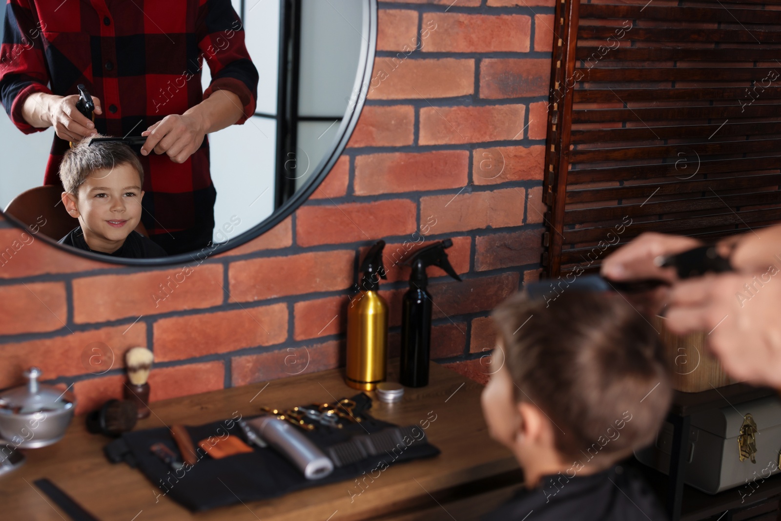 Professional barber working with little boy in barbershop, closeup Photo of Professional barber working with little boy in barbershop, closeup