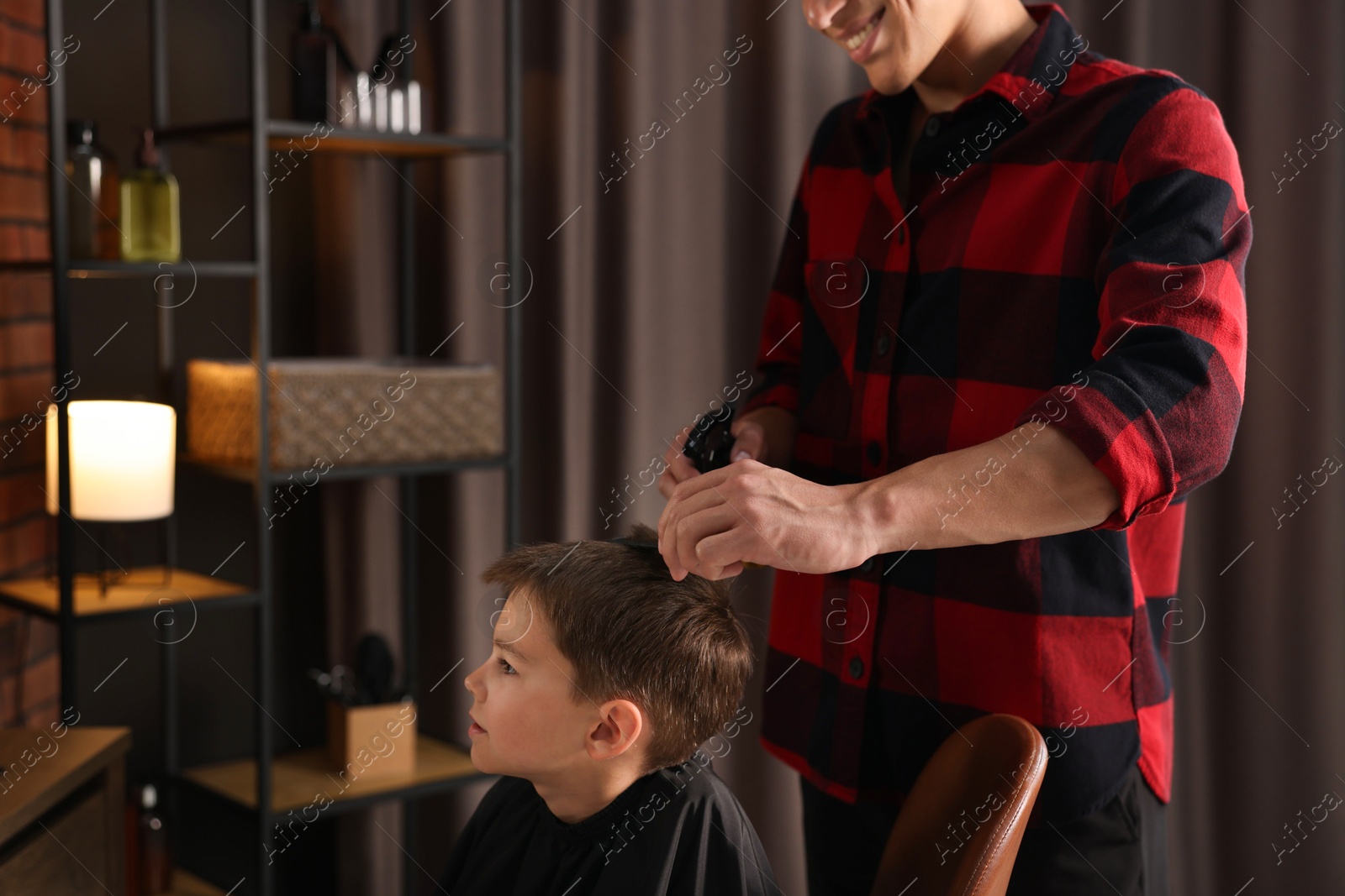 Professional barber working with little boy in barbershop, closeup Photo of Professional barber working with little boy in barbershop, closeup