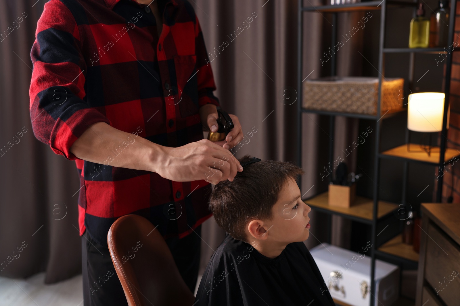 Professional barber working with little boy in barbershop, closeup Photo of Professional barber working with little boy in barbershop, closeup