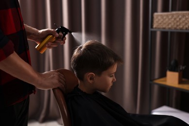 Photo of Professional barber working with little boy in barbershop, closeup