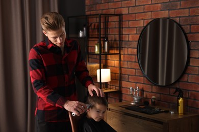 Photo of Professional barber working with little boy in barbershop