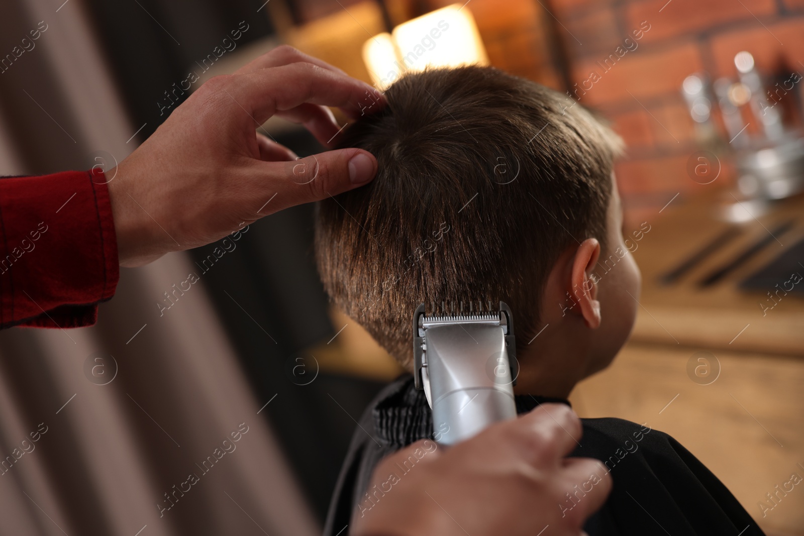 Professional barber working with little boy in barbershop, closeup Photo of Professional barber working with little boy in barbershop, closeup