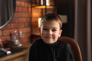 Photo of Portrait of cute little boy in barbershop, space for text