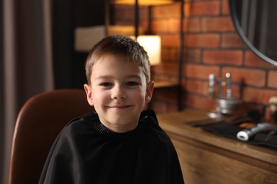 Photo of Portrait of cute little boy in barbershop, space for text