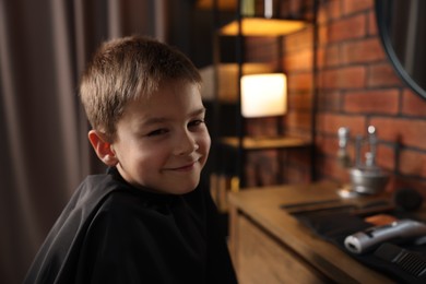 Photo of Portrait of cute little boy in barbershop, space for text