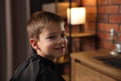 Photo of Portrait of cute little boy in barbershop, space for text