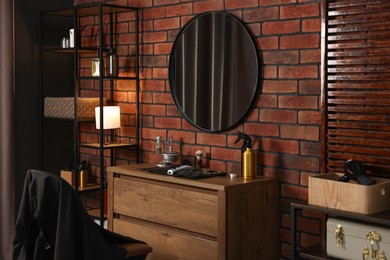 Photo of Different barber's tools on wooden cabinet and mirror in barbershop