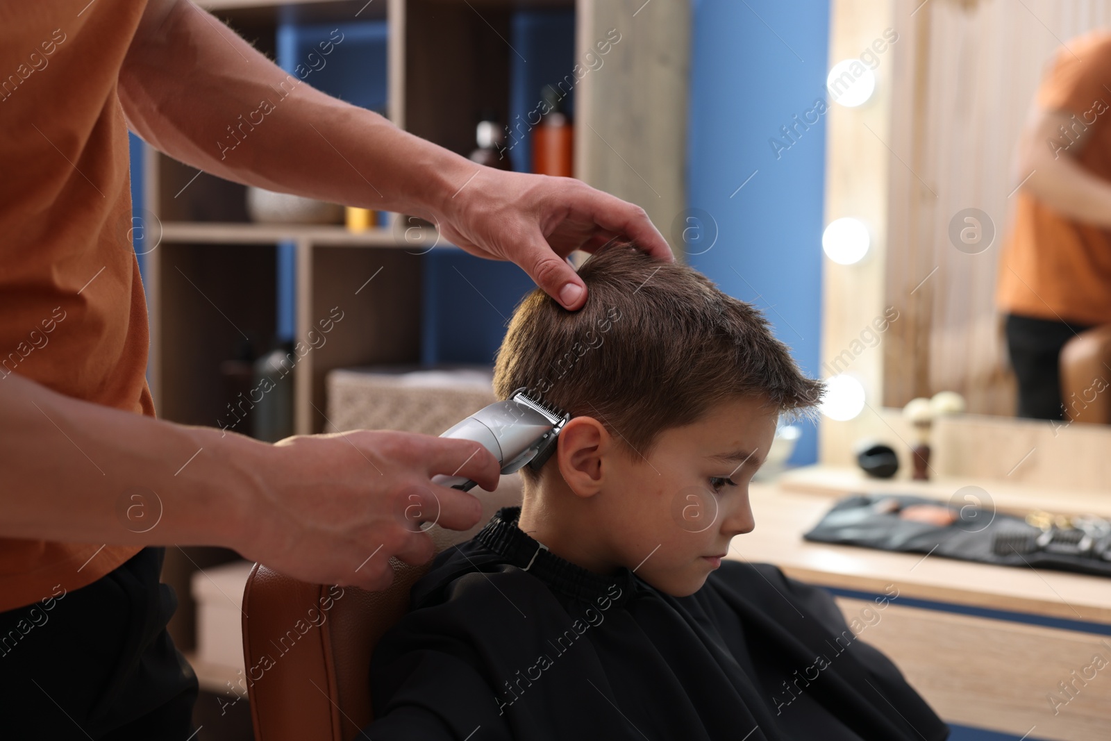Professional barber working with little boy in barbershop, closeup Photo of Professional barber working with little boy in barbershop, closeup