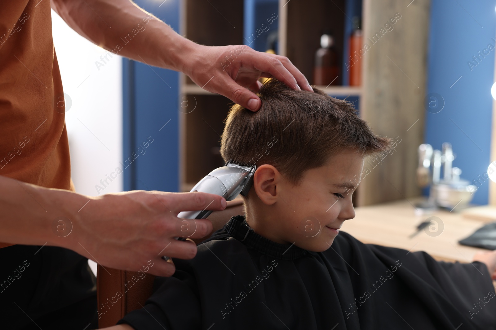 Professional barber working with little boy in barbershop, closeup Photo of Professional barber working with little boy in barbershop, closeup
