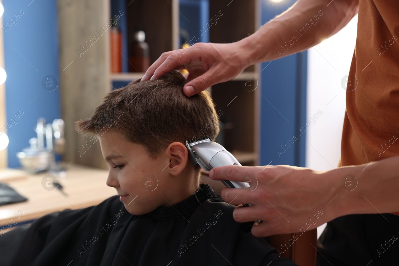 Professional barber working with little boy in barbershop, closeup Photo of Professional barber working with little boy in barbershop, closeup