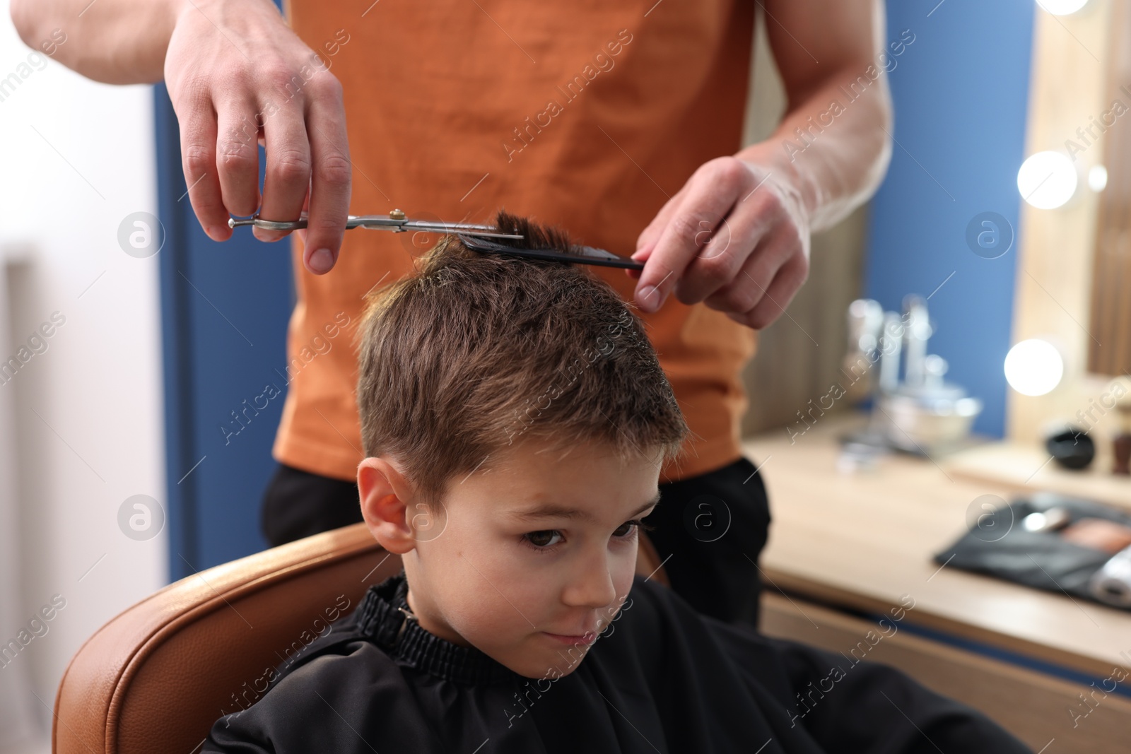 Professional barber cutting boy's hair in barbershop, closeup Photo of Professional barber cutting boy's hair in barbershop, closeup