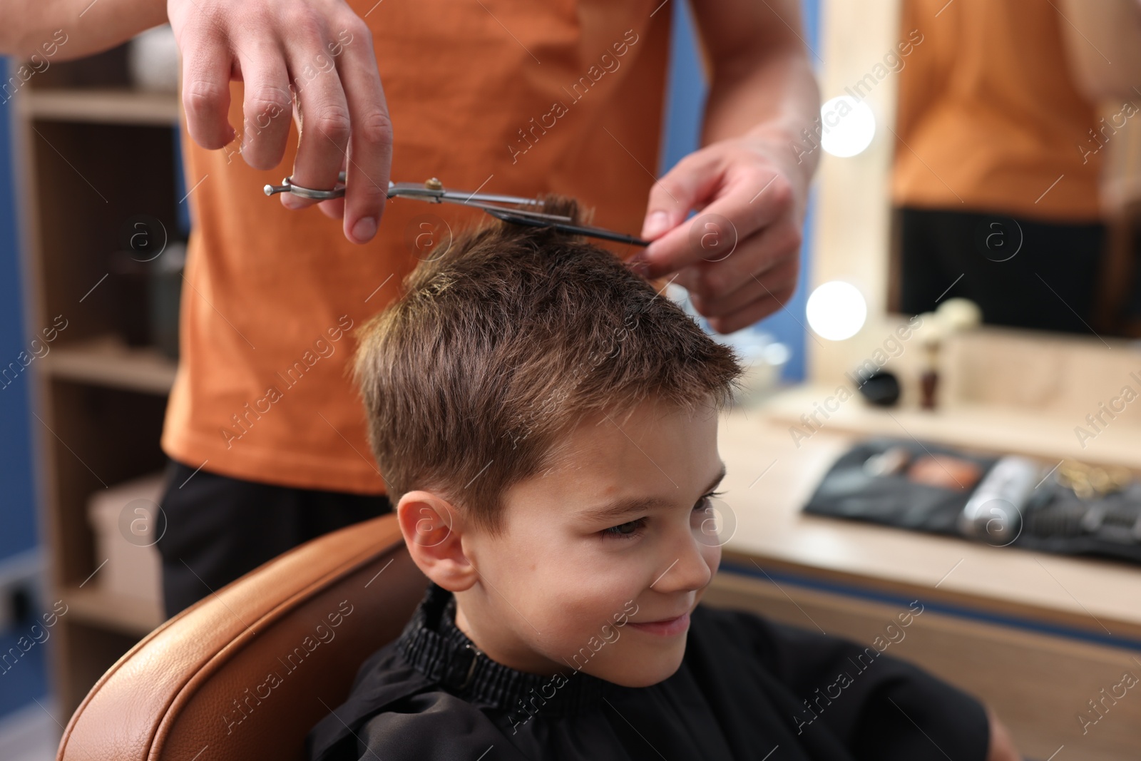 Professional barber cutting boy's hair in barbershop, closeup Photo of Professional barber cutting boy's hair in barbershop, closeup