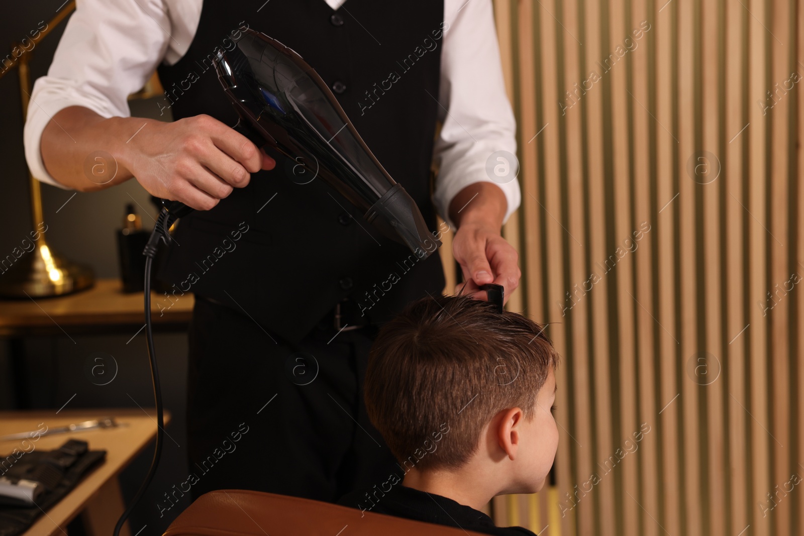 Professional barber blow drying boy's hair in barbershop, closeup Photo of Professional barber blow drying boy's hair in barbershop, closeup