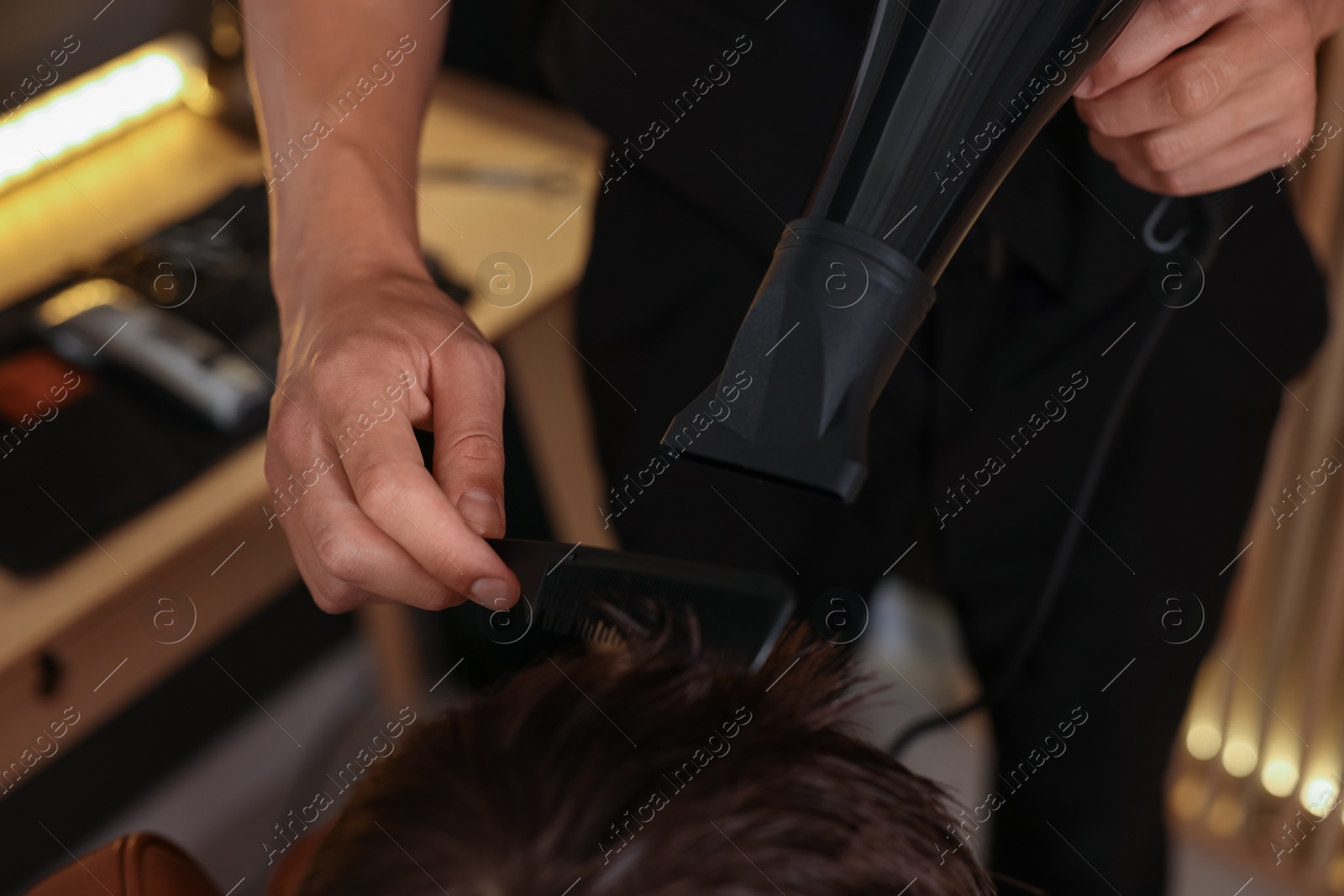 Photo of Professional barber blow drying boy's hair in barbershop, above view
