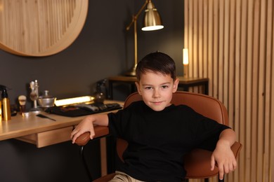Photo of Cute little boy with wet hair in barbershop
