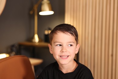 Photo of Cute little boy with wet hair in barbershop