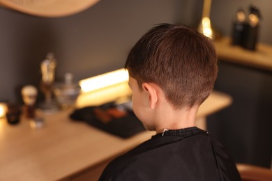 Photo of Little boy with cape in barbershop, space for text