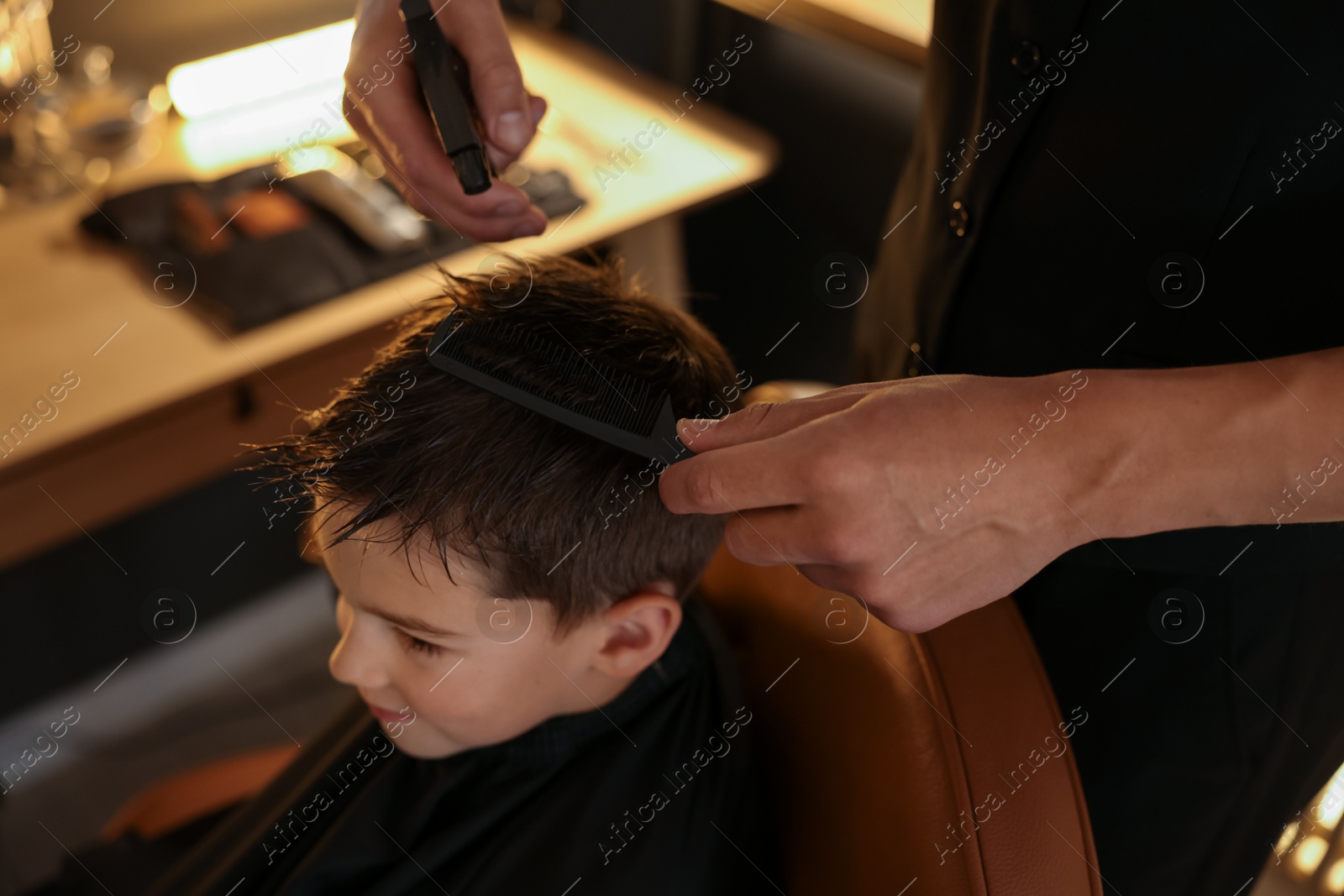 Professional barber working with little boy in barbershop, closeup Photo of Professional barber working with little boy in barbershop, closeup