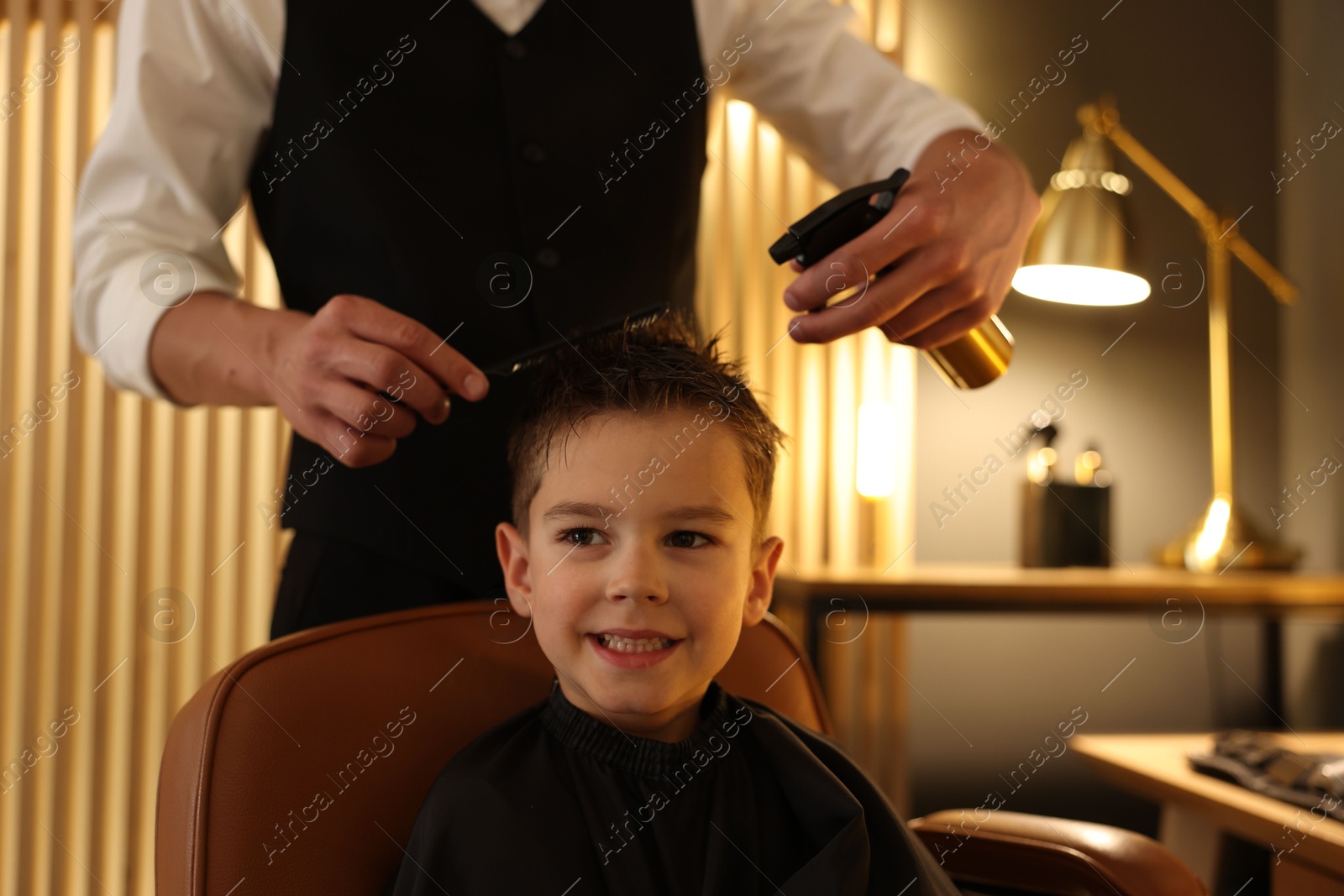 Professional barber working with little boy in barbershop, closeup Photo of Professional barber working with little boy in barbershop, closeup