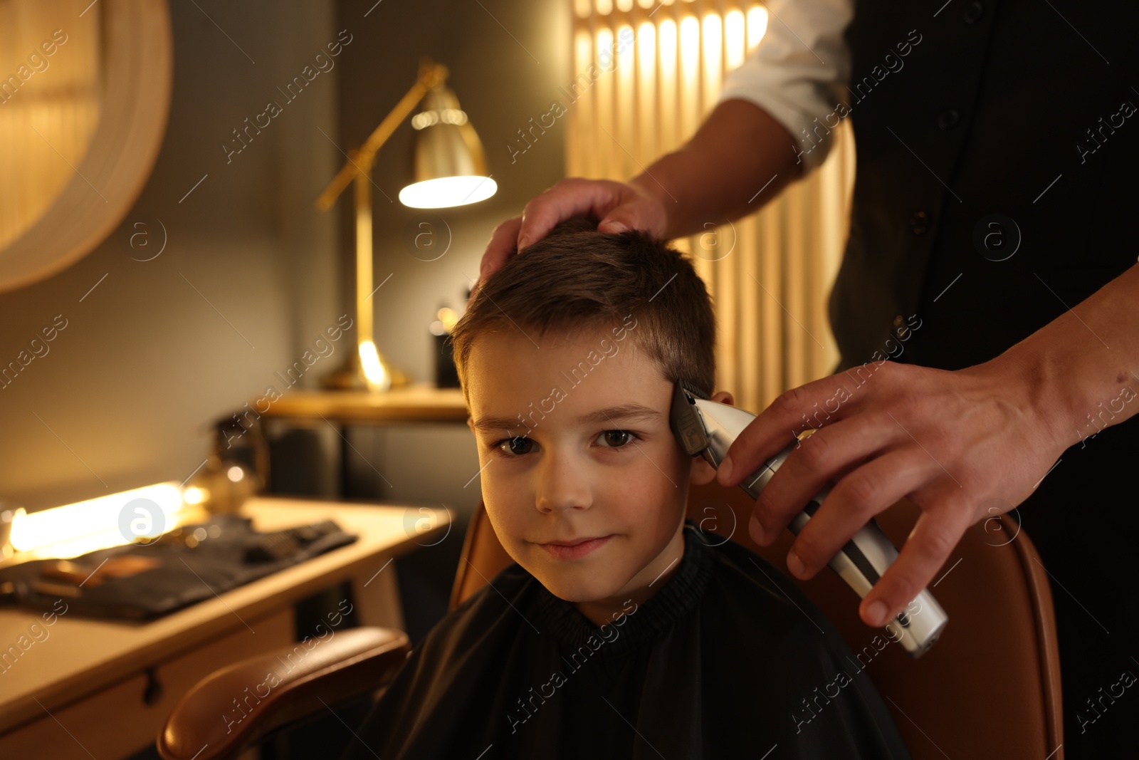 Professional barber working with little boy in barbershop, closeup Photo of Professional barber working with little boy in barbershop, closeup