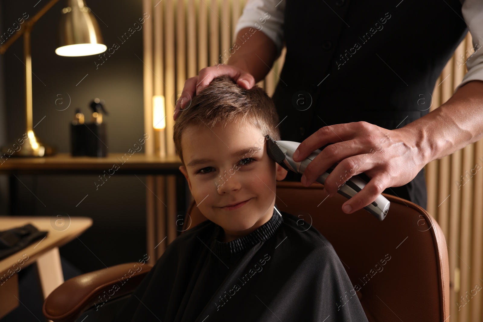 Professional barber working with little boy in barbershop, closeup Photo of Professional barber working with little boy in barbershop, closeup