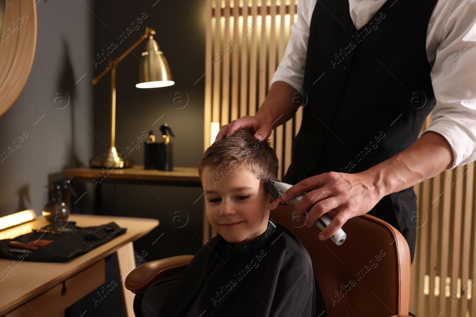 Professional barber working with little boy in barbershop, closeup Photo of Professional barber working with little boy in barbershop, closeup
