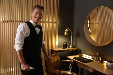 Photo of Happy professional barber with trimmer in barbershop