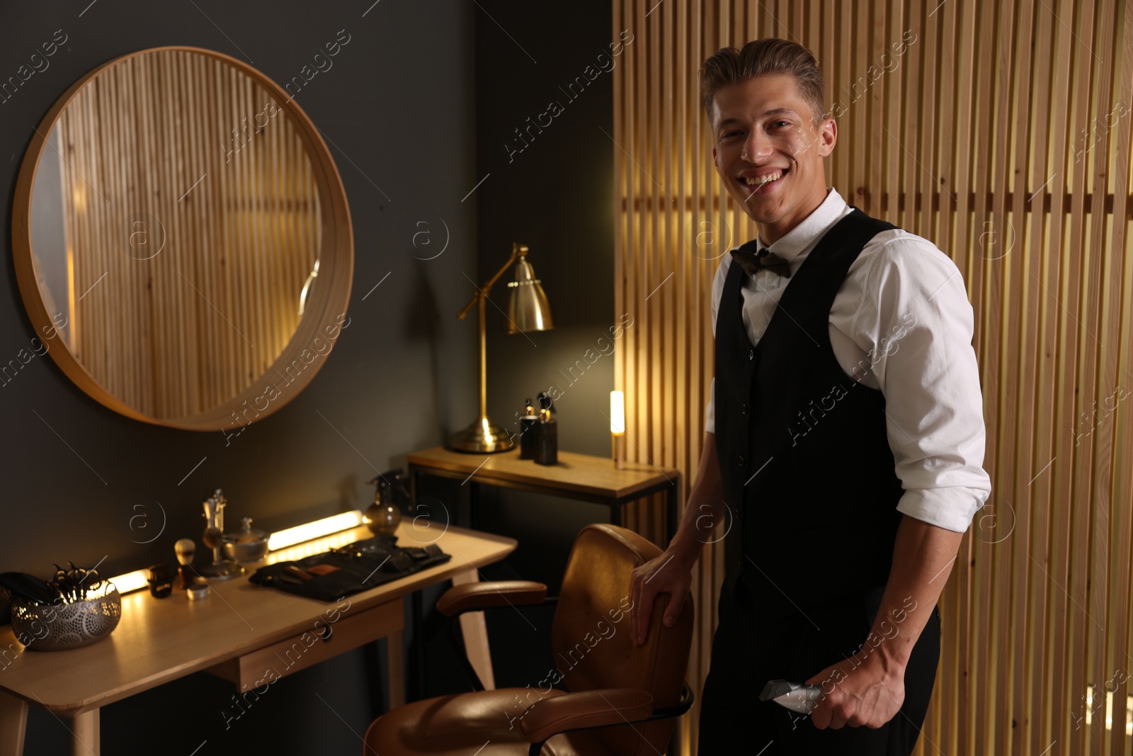 Photo of Happy professional barber with trimmer in barbershop