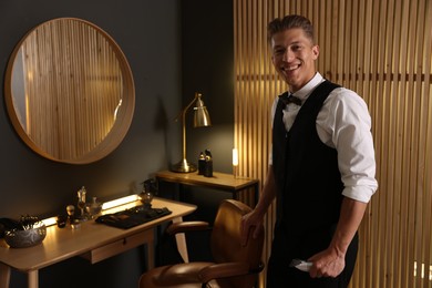 Photo of Happy professional barber with trimmer in barbershop