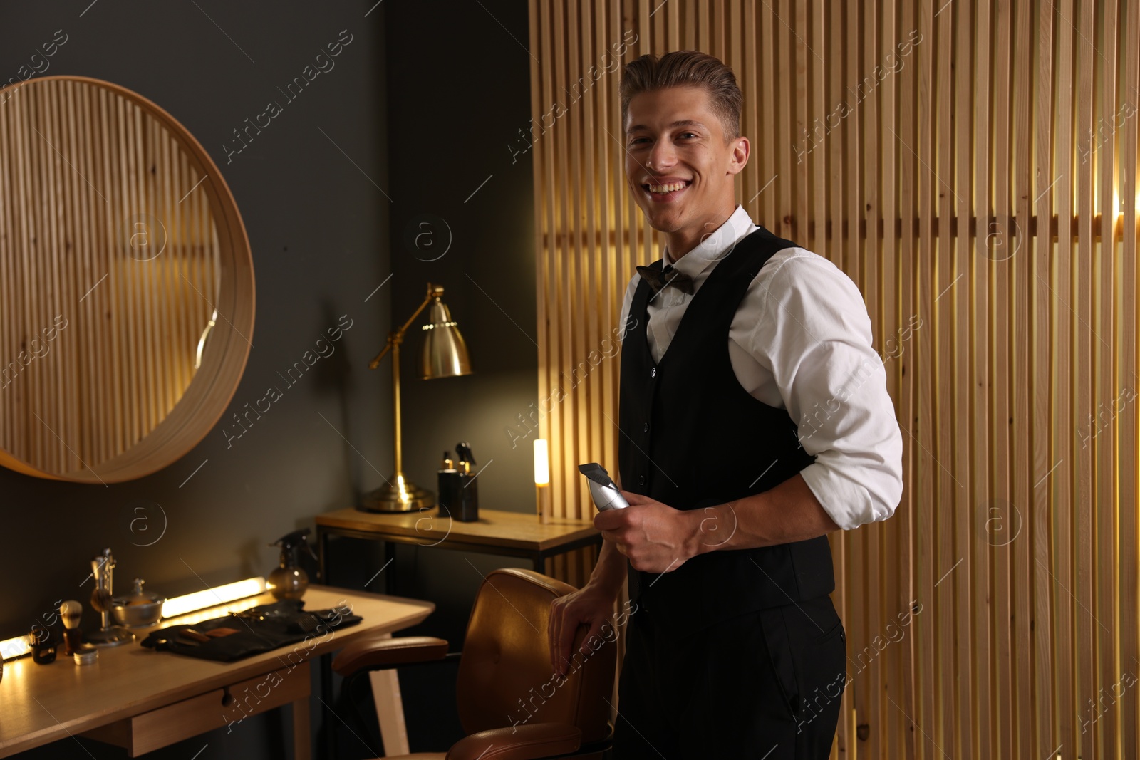 Happy professional barber with trimmer in barbershop Photo of Happy professional barber with trimmer in barbershop