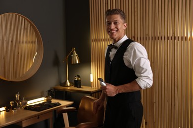 Photo of Happy professional barber with trimmer in barbershop