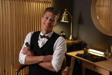 Photo of Happy professional barber with trimmer in barbershop