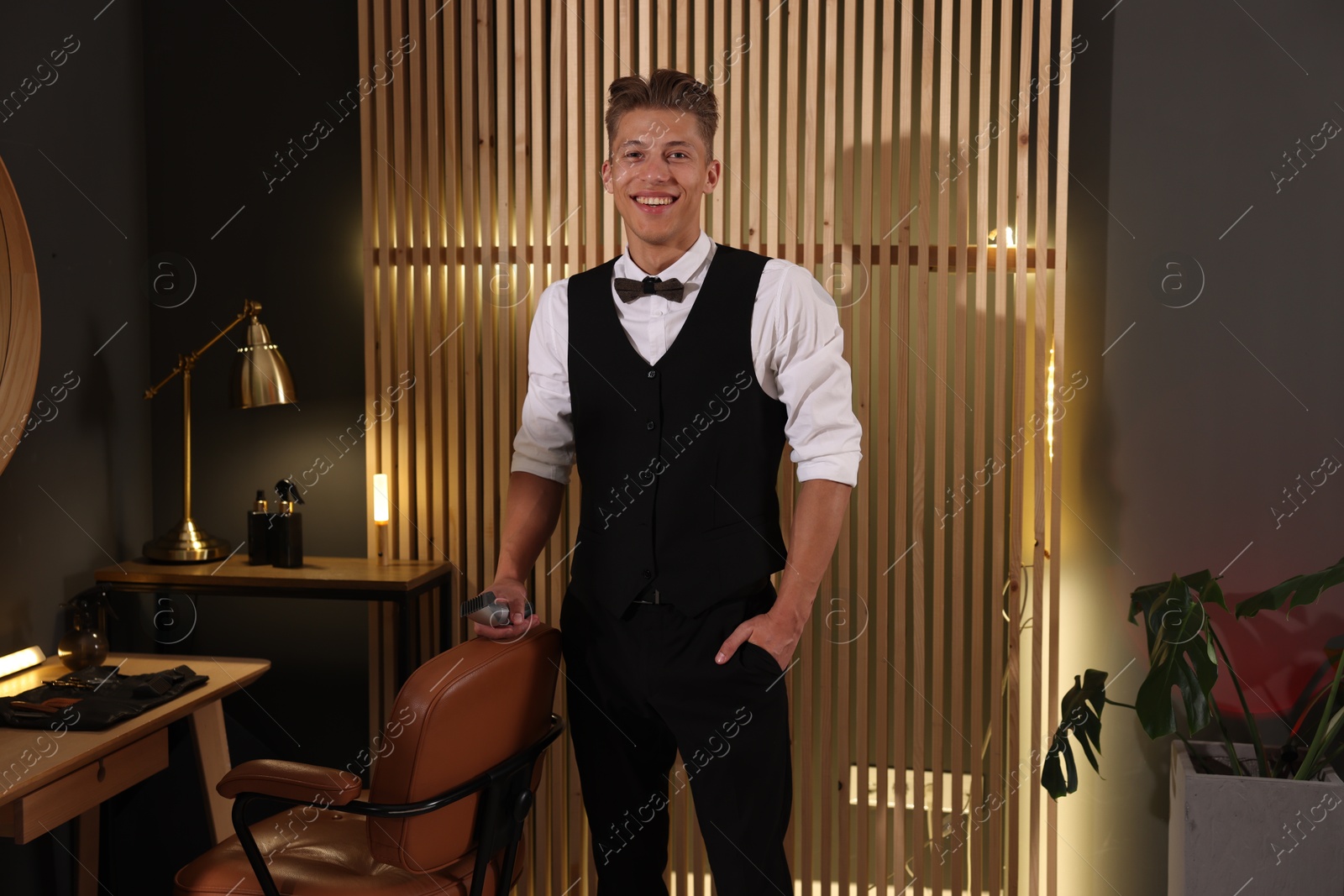 Happy professional barber with trimmer in barbershop Photo of Happy professional barber with trimmer in barbershop