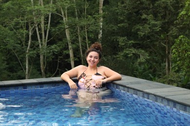 Photo of Happy woman relaxing in swimming pool outdoors