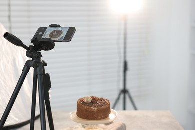 Photo of Shooting chocolate cake with smartphone in studio, selective focus. Professional food photography