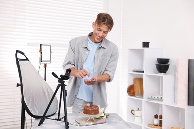 Photo of Man taking picture of chocolate cake in studio. Professional food photography